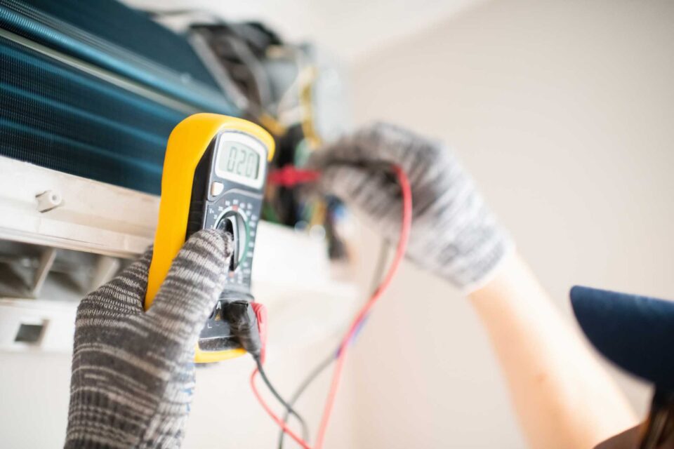 Technician with multimeter repairing air conditioner at home in Lawrenceville, GA